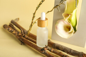 Fototapeta na wymiar Cosmetic dropper bottle with tree branches, flowers and decor on beige background, closeup