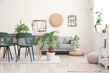 Interior of light dining room with table, sofa and houseplants