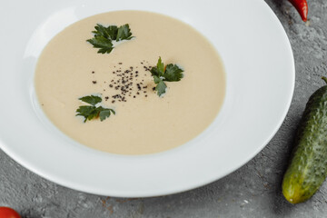 Cheese cream soup with sliced cheese and bread crumbs on a grey background