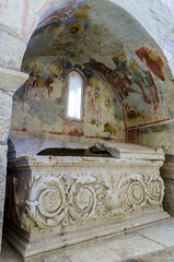 The fragments of colorful ancient fresco of the biblical scene on the arch above stone  sarcophagus...