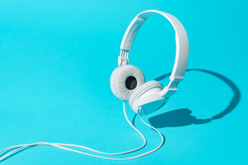 White levitating headphones. Isometric view of headphones on turquoise blue background. Dj headphones with cable.