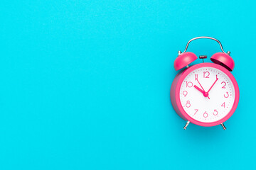 Pink alarm clock over turquoise blue background with copy space. Time management concept.