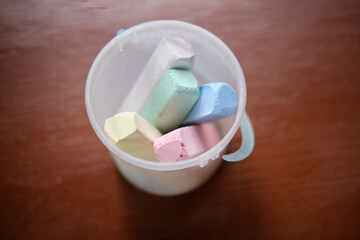 Multicolored crayons in a plastic bucket, side view