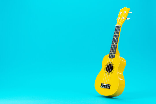 Perspective photo of ukulele with copy space. Yellow colored wooden ukulele guitar on the turquoise blue background.