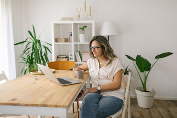 Woman sitting and reading from computer screen at home