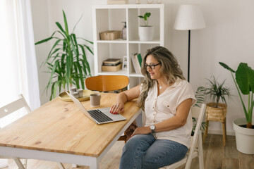 Mature woman sitting and working from home via laptop