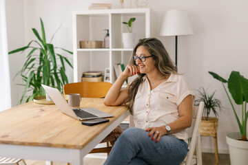 Smiling boomer woman face timing via laptop at home