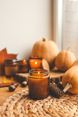 Autumn still life on the windowsill, a burning candle, pumpkins and candles