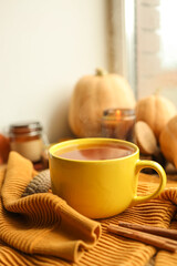 Cup of hot tea, sweater, candle and pumpkins on the windowsill, autumn atmosphere