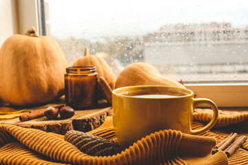 Autumn still life on the windowsill. Cup of tea, pumpkins and candle