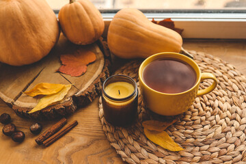 Fototapeta na wymiar A cup of tea and a candle on the window, warm atmospheric autumn photo