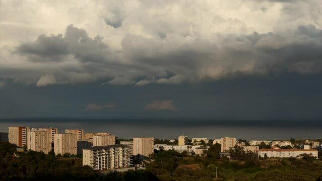 Day to night time-lapse shot of apartment buildings in Bastia while a lot of clouds and rain pass