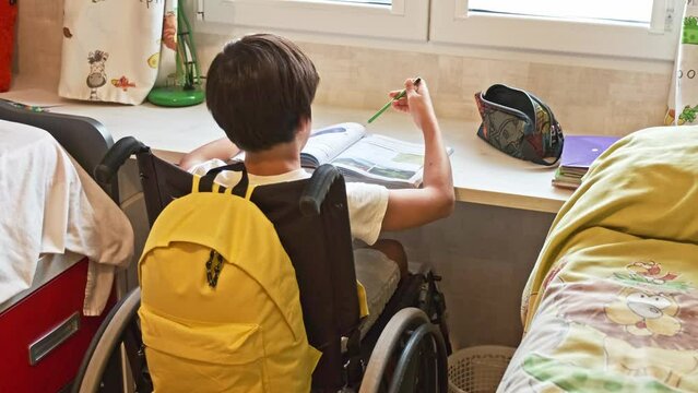 boy in wheelchair doing homework in his room