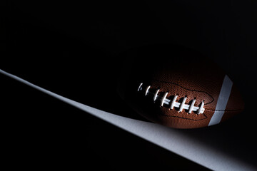American football ball with natural lighting on dark background. Horizontal sport theme poster, greeting cards, headers, website and app - obrazy, fototapety, plakaty