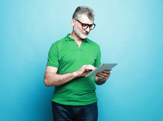 Photo of handsome mature man dressed green t-shirt and eyeglasses smiling typing modern device