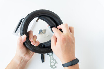 A man carefully looks at the carving of the tire of an electric scooter, fixing a puncture, the...