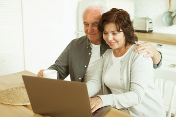 Elderly husband and wife using digital tablet at home, kitchen room