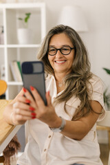 Mature woman video chatting via smartphone at home