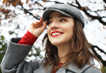 Outdoor portrait of yong beautiful happy smiling woman wearing stylish hat, coat.