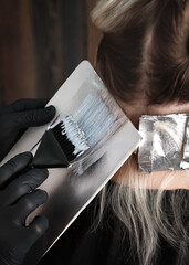 Young woman in a hairdressing salon dyes her hair blond