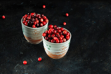 Fresh ripe cranberries in cups on a black background with copy space. selective focus