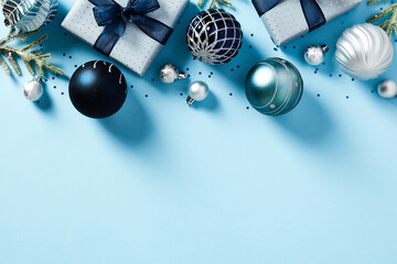 Christmas frame top border made of gift boxes, fir tree branches, blue balls over pastel blue background. Flat lay, top view. Xmas banner mockup with copy space