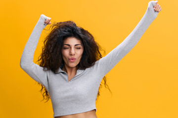 Happy joyful dancing young brunette woman 20s wearing gray sweatshirt posing clenching fists doing...