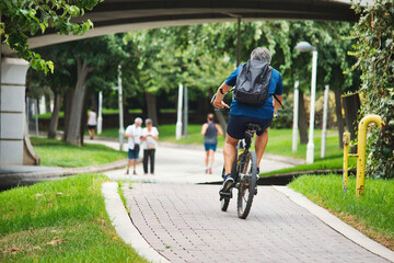 A cyclist riding a push bike in an urban public park on the cycle path