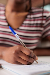 African american woman hand writing with pen in notepad at desk closeup. Student taking notes in...