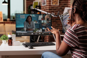 Remote worker talking with team on videocall, online briefing, videoconference communication, telework concept. Woman chatting on virtual meeting, focus on computer screen, back view