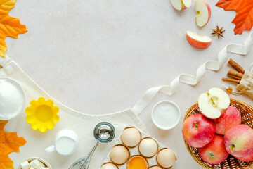 Autumn fall baking food background with flour, milk, sugar, eggs, apples, butter, spices, cupcake spoon on the apron. Cooking healthy apple muffins. Background for recipe. 