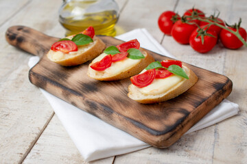 Fototapeta na wymiar Italian bruschetta with roasted cherry tomatoes, mozzarella cheese and basil on a cutting board. top view