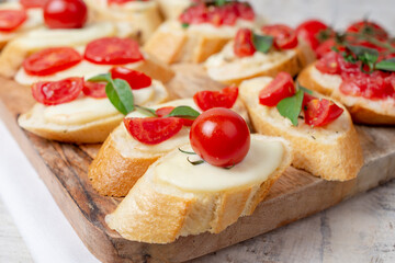 Fototapeta na wymiar Italian homemade bruschetta with roasted cherry tomatoes, mozzarella cheese, basil and herbs on a cutting board