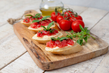 Fototapeta na wymiar Homemade bruschetta with tomatoes, mozzarella cheese and basil on cutting board on a wooden background. Traditional italian appetizer or snack, antipasto. Top view, flat lay.