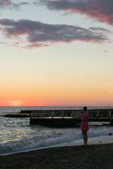 Fototapeta premium a girl takes a selfie on her phone on the seashore at sunset