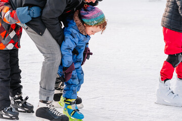 Soft,Selective focus.Funny moment fell on the ice skating rink. Activity, Adult, Child, Childhood, Daughter. Mom with baby boy 3-5 years old, learn train, ride winter city rink, ice skating.