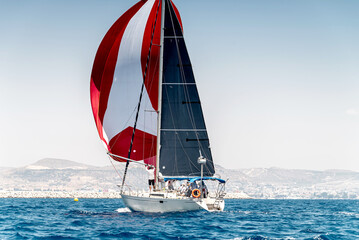 Sailing boat on a calm water with red sail during the regatta