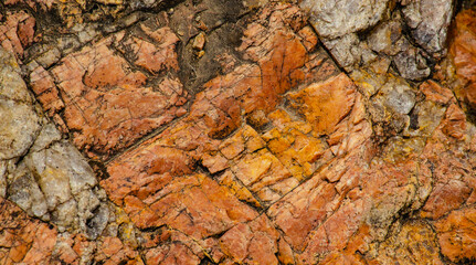 The texture of stone wall corrosion or grunge stone texture use for web design and wallpaper background. Surface of ancient rock layers brown, yellow, red