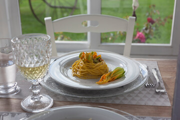 lunch set table in a bay window with zucchini floers spaghetti