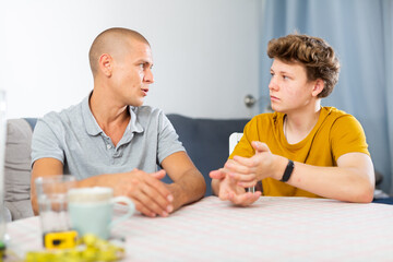 Father and his young son talking about something while sitting at the table