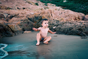 Bebé niño jugando con la arena y el agua en la playa