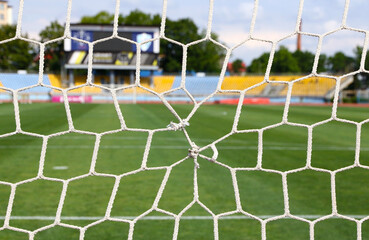 Close-up torn goal net, details of football soccer stadium. View behind the net