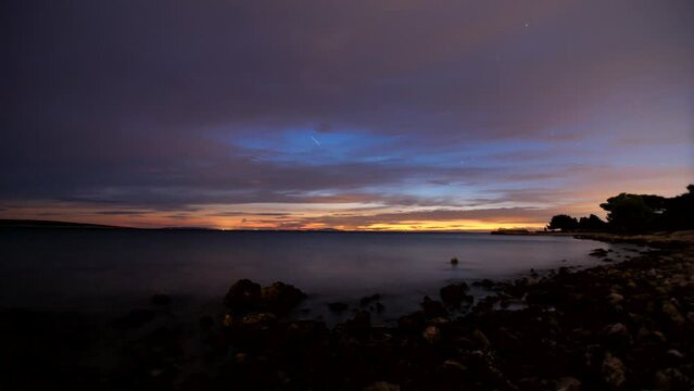 Time lapse shot of a rocky beach on the island of Pag in dusk of a summer evening with some clouds and stars.