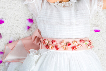 Fototapeta na wymiar dress and outfit for holy Communion girl with pink flower belt