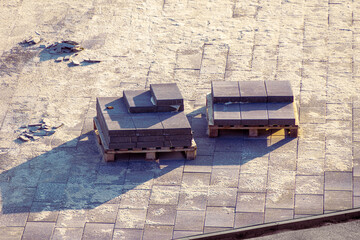 square paving slabs from a cement mixture lie on pallets, among the square