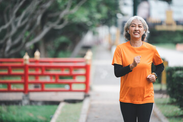 white-haired elderly person exercising in the park early in the morning.