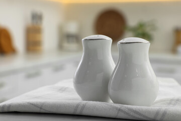 Fototapeta na wymiar Ceramic salt and pepper shakers with napkin on table in kitchen. Space for text