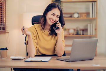 Asian business woman have the joy of talking on the phone, laptop and tablet on the office desk.