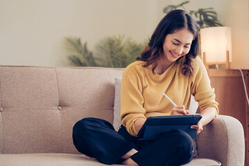 Fototapeta premium Confident pretty asian business woman working with laptop while doing some paperwork at home