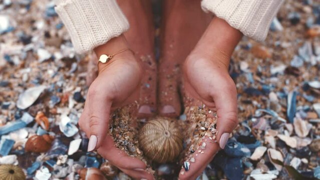 Woman on beach, Bali ocean and shell fossil in manicure hands on summer vacation. Calm island holiday peace, free travel experience and barefoot pedicure feet seaside sand stones from natural marine